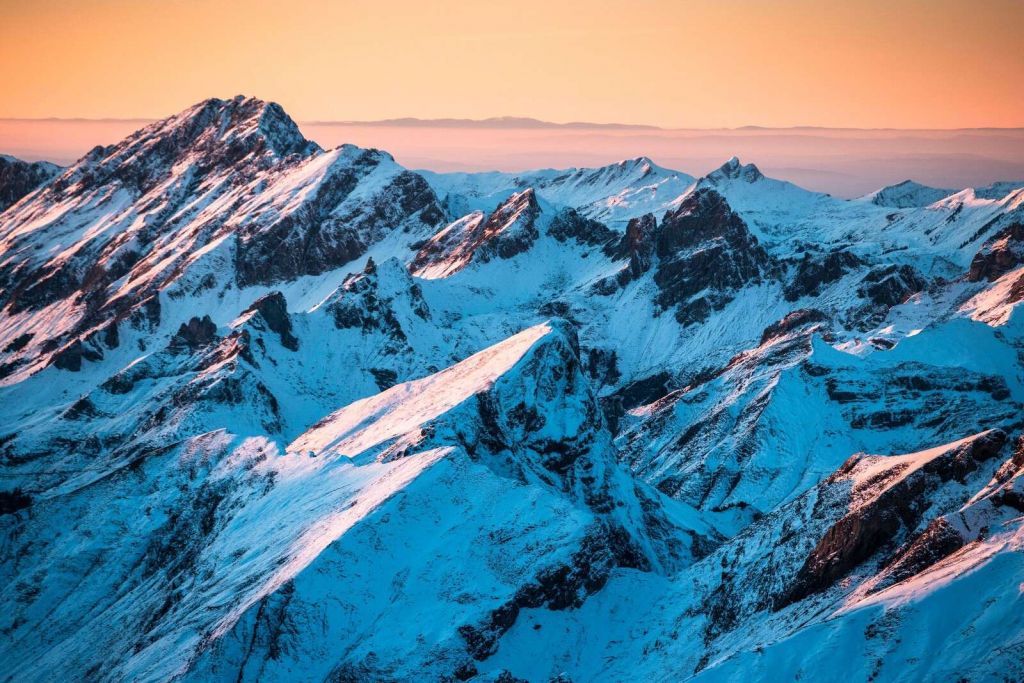Lever du soleil sur un massif montagneux enneigé.