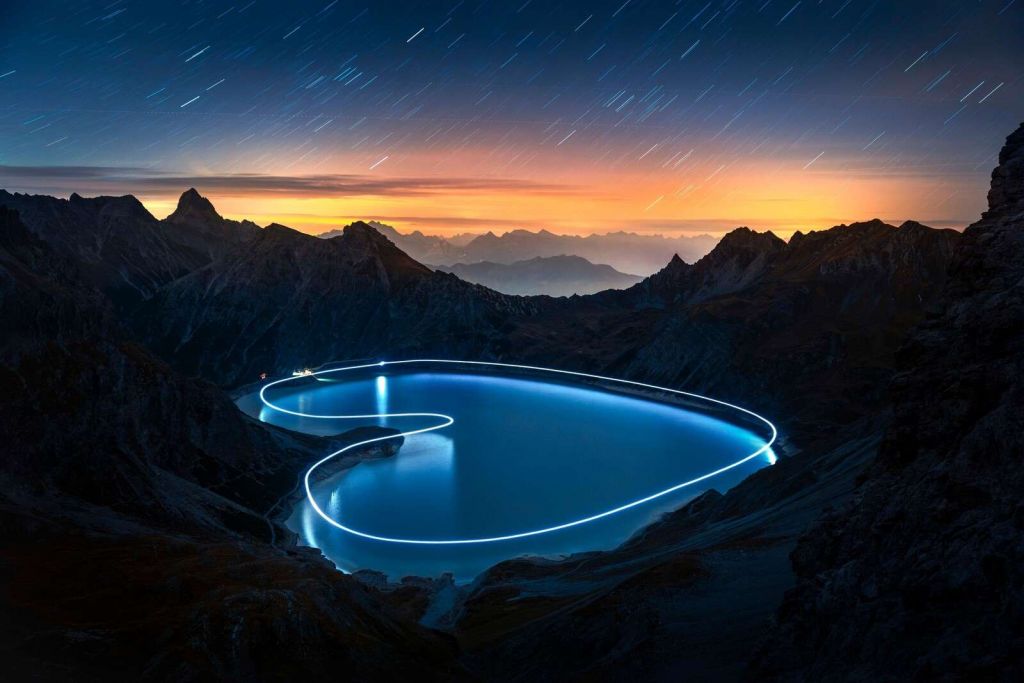 Chemin lumineux autour d'un lac de montagne la nuit