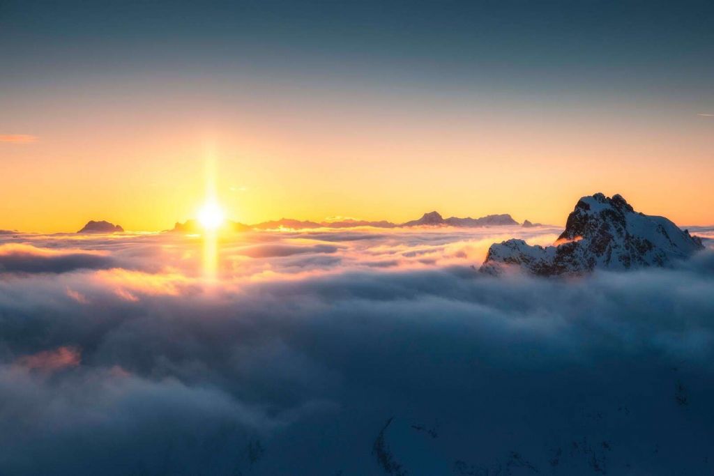 Lever de soleil au-dessus de la mer de nuages et des sommets de montagne.