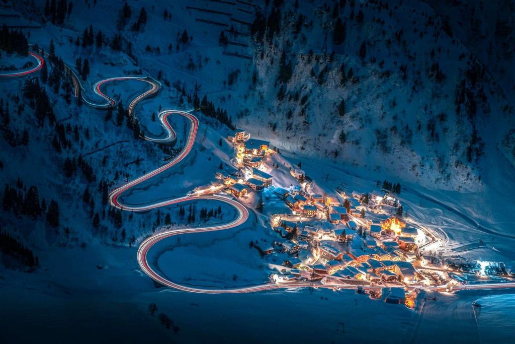 Village de montagne illuminé avec une route de montagne sinueuse