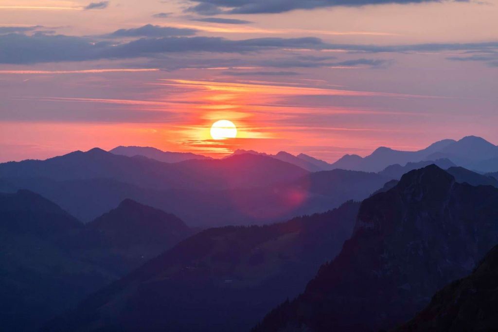 Coucher de soleil au-dessus de couches de montagnes violettes.