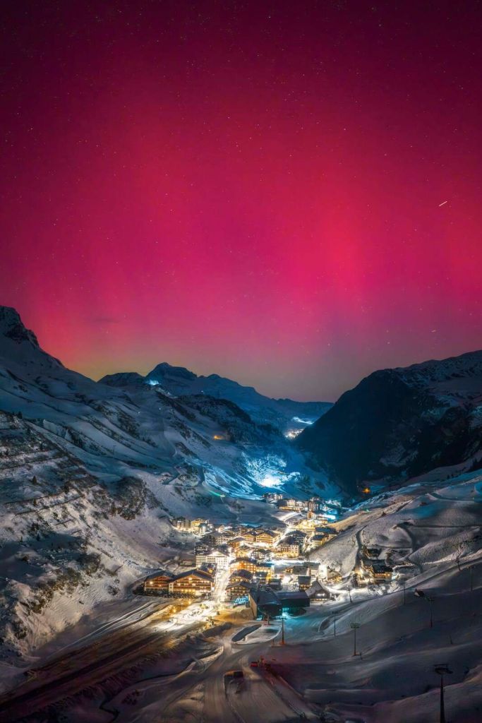 Aurore bor√©ale rose au-dessus d‚Äôun village de montagne