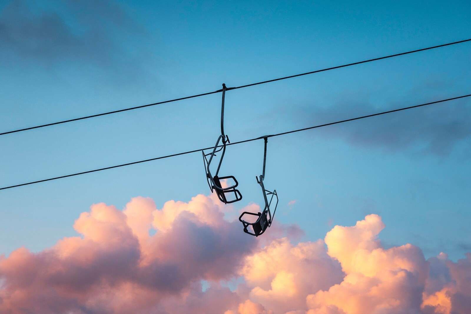 Télésiège au-dessus de nuages roses du soir.