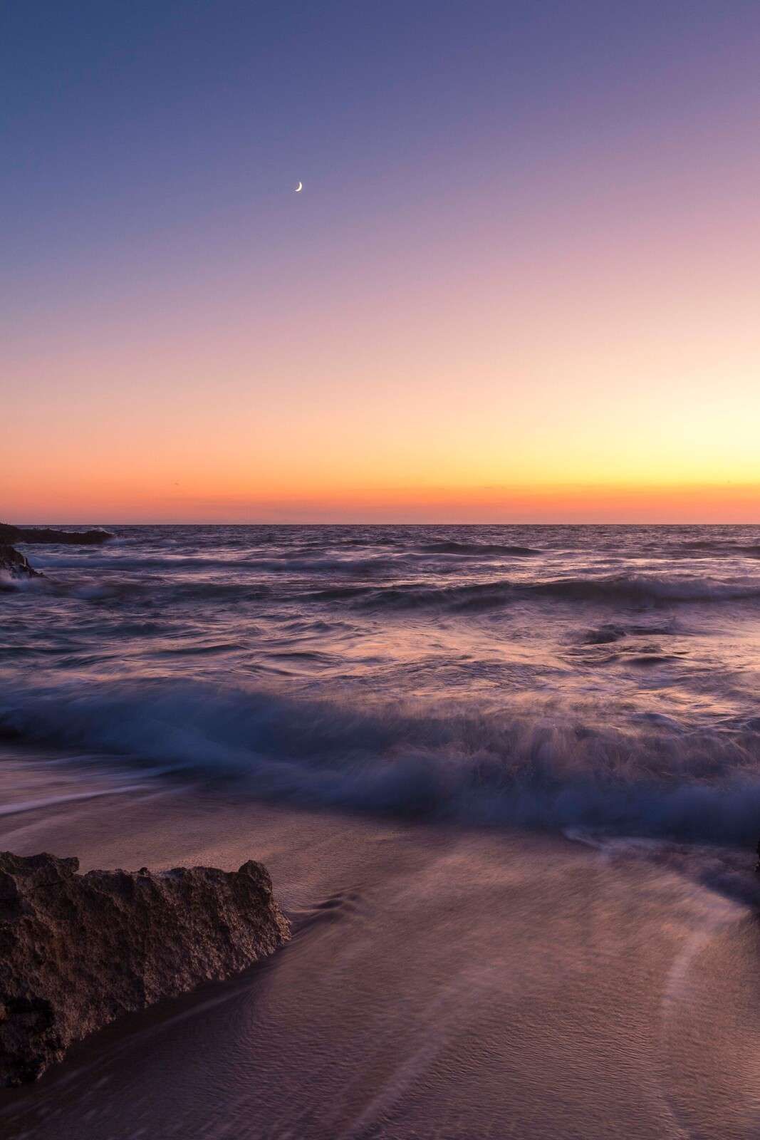Lumière de lune sur des vagues violettes au coucher du soleil.
