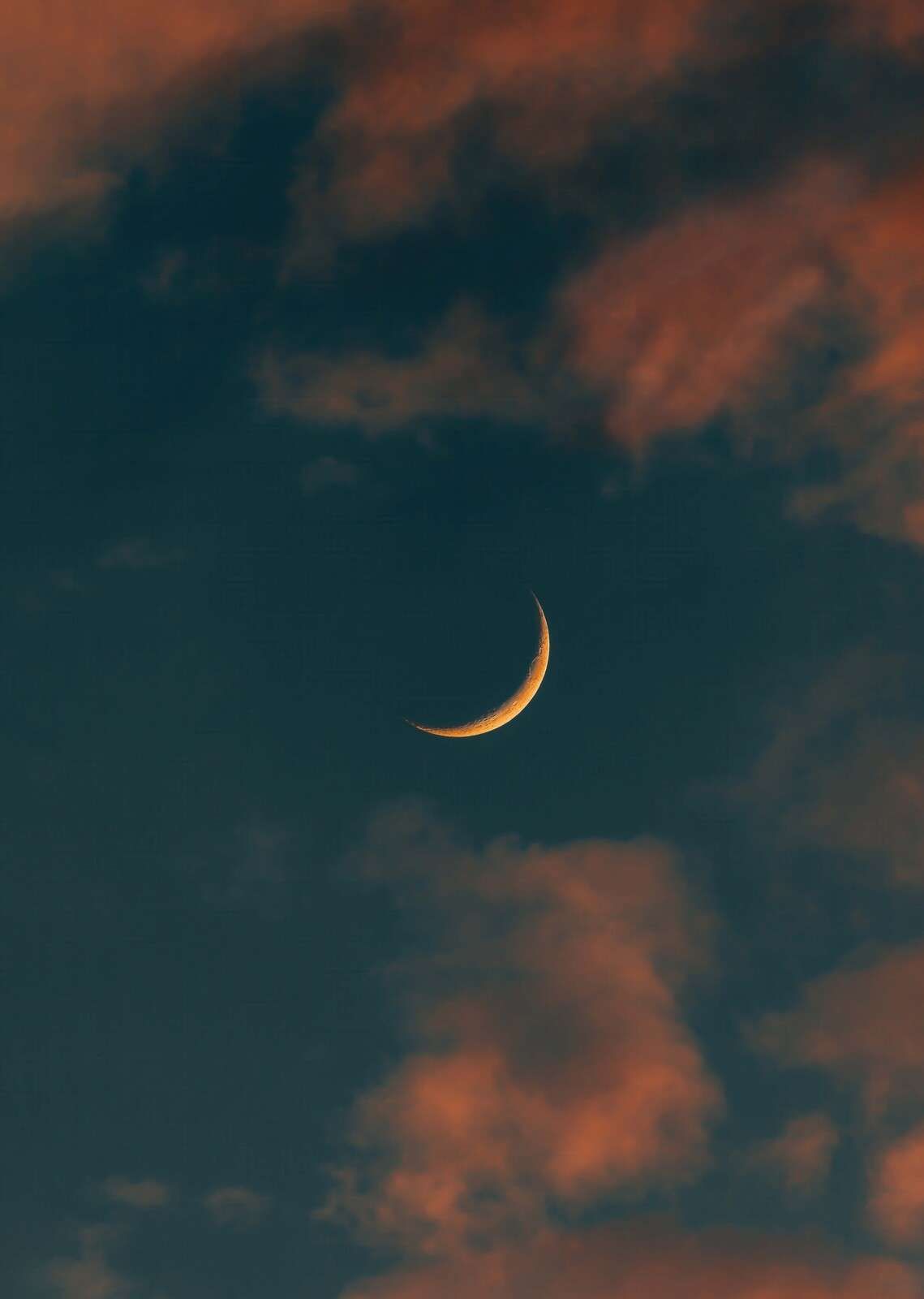 Petite lune entre des nuages ardents